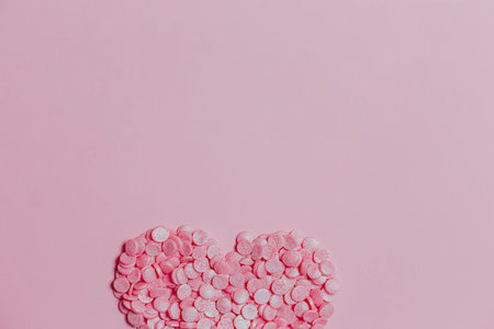 Valentine's Day concept. Top view photo of heart shaped confectionery sprinkles on light pink...