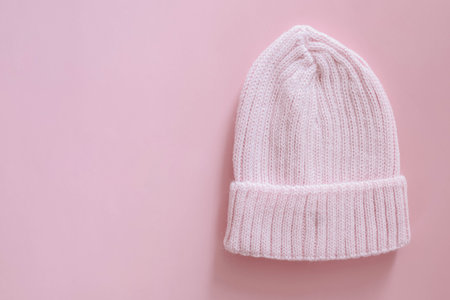 Knitted hat for a newborn for walking in autumn or spring on a pink background. Clothes for newborns.の写真素材