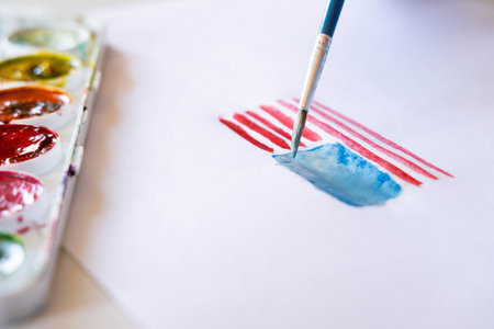 The American 4th of July flag is painted with watercolors by a child's hand. Patriotism, Independence Day, Flag Day Concept. Day of Remembranceの写真素材