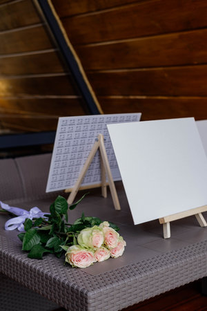 Small easels stand on the terrace of the house. Rose flowers lie near the easels.の写真素材