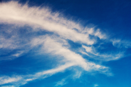 Feather clouds illuminated by the sun against a bright blue skyの写真素材