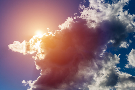 Beautiful fluffy clouds illuminated by the sun against a blue sky (background, toned)の写真素材
