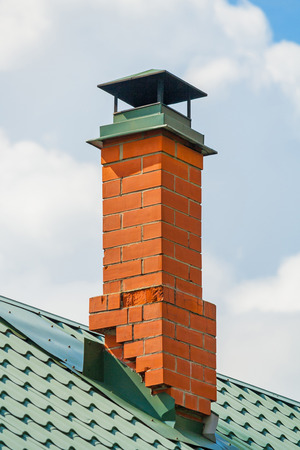 Red brick chimney pipe at home a background of cloudy skyの写真素材
