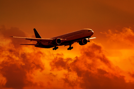Dramatic view of a dark silhouette of aircraft against a red sunset skyの写真素材