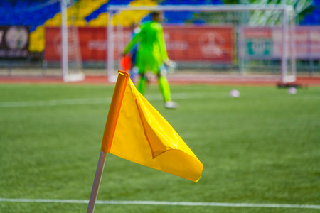 Close up view of a yellow corner flag on the football field on a background of the players in blurの写真素材