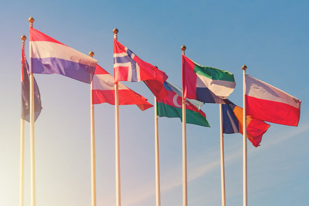 Flags of different countries of the world flutters in the wind against a sunlight (toned)