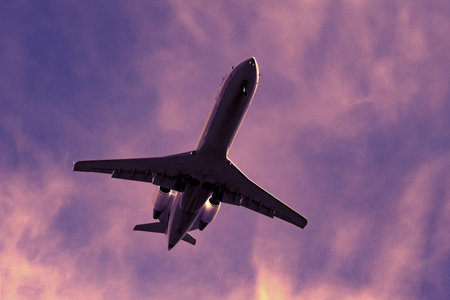 Bottom view of a dark silhouette of airplane in the  dramatic purple evening skyの写真素材