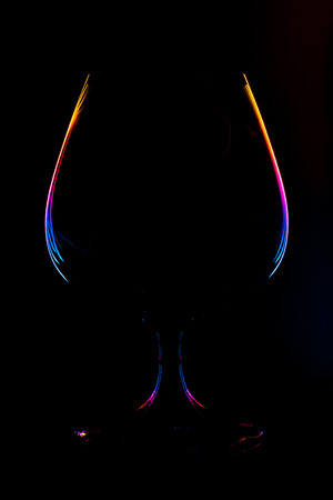 Abstract view on a wine glass silhouette with lighted multi-colored gradient edges on a black background (concept, copy space)の写真素材