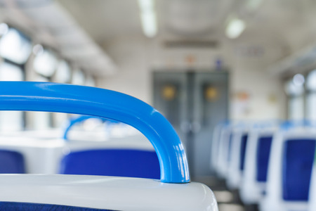 Close up view on a blue handhold on a background of Interior of a passenger train in blurの写真素材