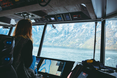 Traveller girl manages the ferry, looking at the river and view of the fjord and mountains, travel...