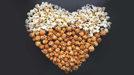 Love Cinema concept of popcorn arranged in a heart shape. Assorted popcorn set background. Sweet and salty popcorn on black background.の写真素材