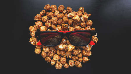 Abstract image of viewer, 3D glasses and popcorn on black background. Still life, top view, flat lay. Concept cinema and entertainmentの写真素材
