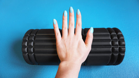 Foam Roller Gym Fitness Equipment Blue background self Myofascial Release - MFR. Hand holds a...