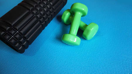 Foam Roller with green dumbbells Gym Fitness Equipment Blue background self Myofascial Release - MFR.の写真素材