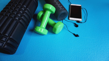 Foam Roller with green dumbbells and water bottle and telephone with headphones - Gym Fitness...