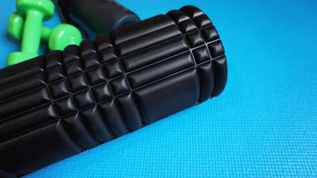 Foam Roller with green dumbbells Gym Fitness Equipment Blue background self Myofascial Release - MFR.の写真素材