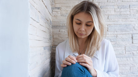 Sad or Depressed Young Beautiful Woman at home on brick wall background