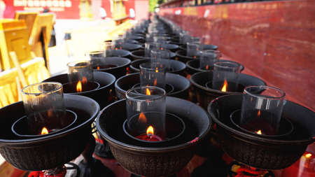 Burning big red candles in Buddhist temple in Chinaの写真素材