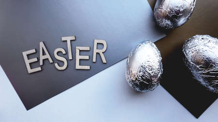 Eggs in foil on silver background. Easter concept banner. With text Easterの写真素材
