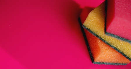 Sponges - close-up. Household cleaning concept. Colorful orange pink yellow sponges on pink background, soft focus, copy text.の写真素材