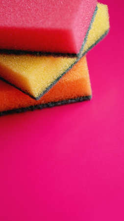 Sponges - close-up. Household cleaning concept. Colorful orange pink yellow sponges on pink background, soft focus, copy text.の写真素材