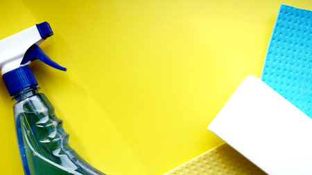 Housework, housekeeping and household concept - cleaning rag, detergent spray on yellow background