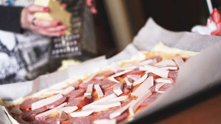 Closeup hand of chef baker making homemade pizza. Female hands rubbing cheese on pizzaの写真素材