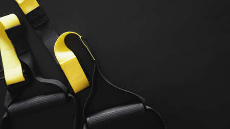 Black and yellow strap functional training equipment on grey background. Sport accessories. Fitness and Gym workout items for Healthy. Banner TRXの写真素材
