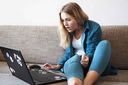 Shocked young woman looking at laptop screen at home seeing something unbelievable on computer. Bad...
