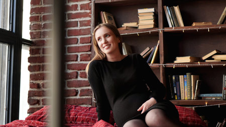 Young pretty pregnant woman in black dress in studio - loft interior