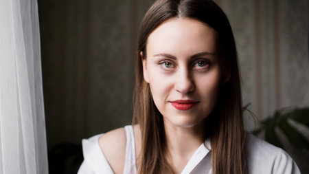 Portrait of attractive brunette woman. Home portrait of a woman with red lips in a white shirt