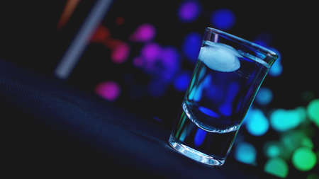 Drink shot with ice in bar on neon color abstract backgroundの写真素材