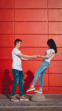 Young smiling couple in love man holding attractive woman hand, spending time together, enjoying - red backgroundの写真素材