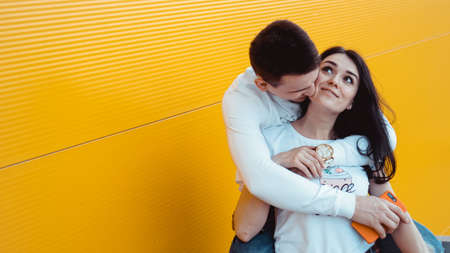Image of Young lovely couple posing together and hugging over yellow backgroundの写真素材