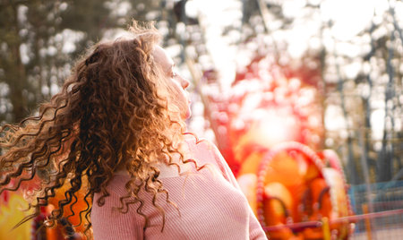 Girl chilling in amusement park in weekend morning. Laughing good-humoured female model with curly...