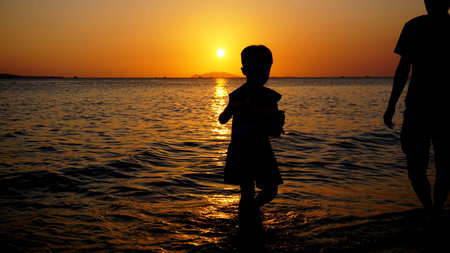 Father and child playing on the beach at the sunset time. Concept of friendly family.の写真素材