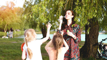 Woman and children play with soap balloons. Romantic portrait of young woman with soap balloons....
