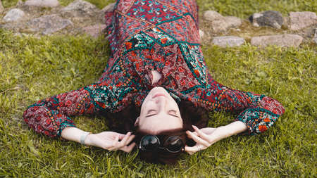 Young woman lying on grass looking up in the sky. People relaxing in outdoors.の写真素材