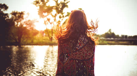 Back of woman resting on the nature near the river. Sunny simmer dayの写真素材