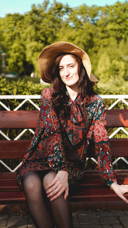 Fashionably dressed young pretty woman on the street on a sunny day. Beautiful girl in dress and hat...