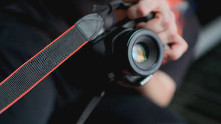 Young man photographer holds camera. Photographer concept. Blurred background for bannerの写真素材