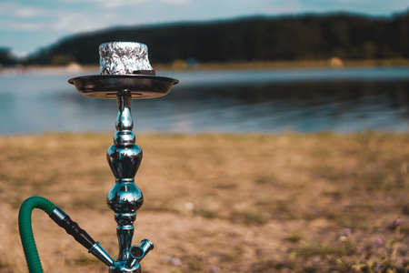 Summer vacation, activity. environment, travel and hookah smoking concept. Hookah bowl stands in nature by the river close upの写真素材