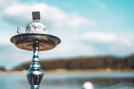 Summer vacation, activity. environment, travel and hookah smoking concept. Hookah bowl stands in nature by the river close upの写真素材