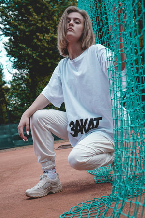 Stylish modern woman In white T-shirt with the inscription Sunset in Russian language - poses on...