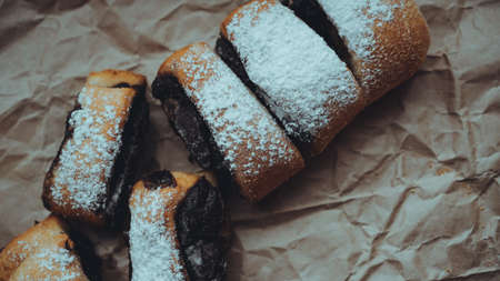 Freshly Baked Chocolate Rolls with a delicious filling, sprinkled with powdered sugar. Against the background of brown craft paperの写真素材