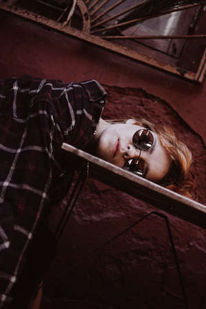 Portrait of woman with short red hair in sunglasses, head lies on table. Fatigue conceptの写真素材
