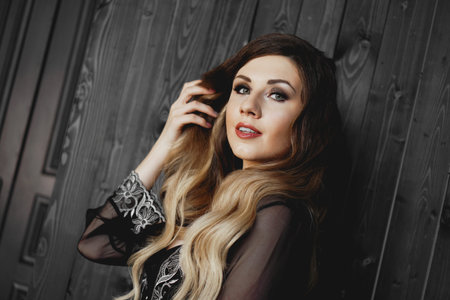 Young pretty woman, wearing transparent black peignoir night gown in dark room. Beautiful Sexy woman...