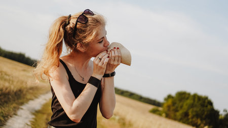 Woman holding delicious taco, closeup. The woman is in a picturesque field
