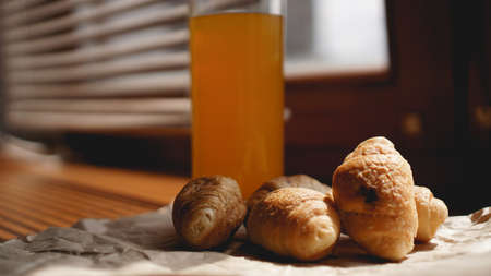 Freshly baked croissants with orange juice on kraft paper. Closeup photography of fresh delicious dessert for breakfast.の写真素材