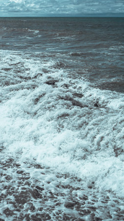 A breaking wave and stormy sea in a vertical panorama format.